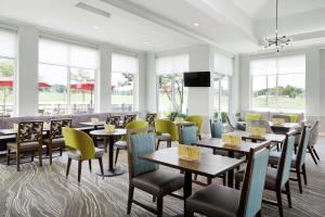 ein Restaurant mit Tischen, Stühlen und Fenstern in der Unterkunft Hilton Garden Inn Cincinnati Northeast in Loveland