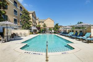 una piscina con sillas y sombrillas en un hotel en Homewood Suites by Hilton Dallas/Allen, en Allen