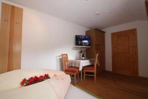 a bedroom with a bed and a table and a television at Landhaus Granat in Mayrhofen