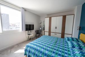 a bedroom with a blue and white bed and a window at Happy 70's - Family Place in Villeurbanne
