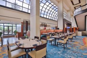 a restaurant with tables and chairs and a large window at Hilton Miami Airport Blue Lagoon in Miami