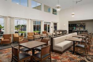 a restaurant with tables and chairs and windows at Homewood Suites By Hilton Kansas City Speedway in Kansas City