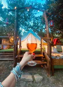 a person holding a glass of wine in front of a tent at Yurta con uso piscina e vista meravigliosa in Dicomano