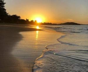 um pôr do sol na praia com a maré a chegar em Pousada Estrela da Manhã em Penha