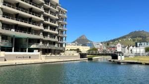 a large apartment building next to a river with a bridge at 501 Canal Quays in Cape Town