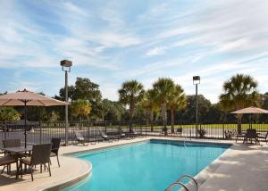 einen Pool mit Stühlen, Tischen und Sonnenschirmen in der Unterkunft Hilton Garden Inn Beaufort in Beaufort