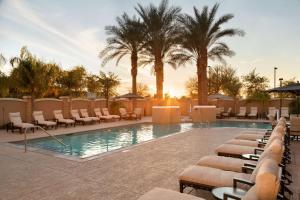 a swimming pool with lounge chairs and palm trees at Hilton Phoenix Chandler in Chandler