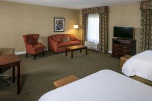 a hotel room with a bed and a couch and a television at Hampton Inn & Suites Toledo-Perrysburg in Rossford