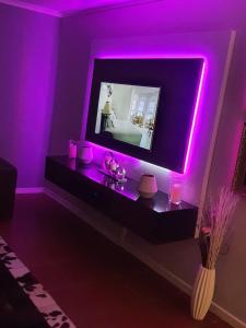 a room with a tv with purple lights on it at 67@18th Avenue Beach View, in East London +14 photos