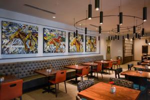 a restaurant with tables and chairs and paintings on the wall at Hilton Garden Inn Louisville Mall Of St. Matthews in Louisville