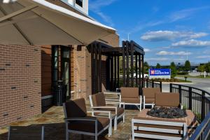 a patio with chairs and tables and an umbrella at Hilton Garden Inn Louisville Mall Of St. Matthews in Louisville