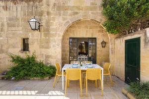 una mesa con sillas amarillas frente a un edificio en Gozo Escape, en Għasri