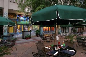 un patio con mesas y sillas y una gran sombrilla verde en DoubleTree by Hilton Hotel Tallahassee, en Tallahassee