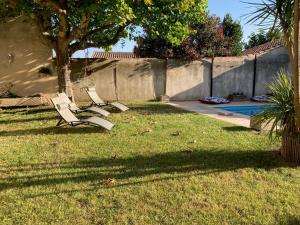 duas cadeiras num quintal com uma árvore e uma piscina em Entre vigne et Camargue em Générac
