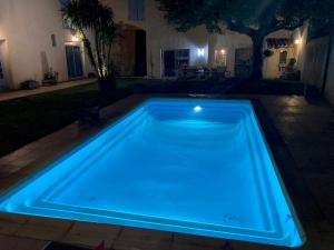 uma piscina com uma luz azul num quintal à noite em Entre vigne et Camargue em Générac