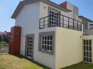 una casa bianca con una porta rossa di Agradable casa para descansar en Villas de Campo a Calimaya de Díaz González