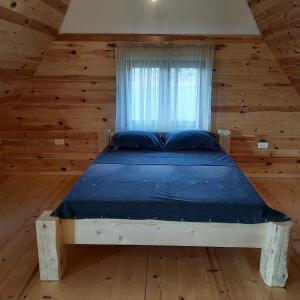 a bed in a wooden room with a window at Zelenova koliba in Žabljak