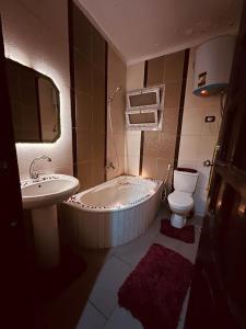 ein Badezimmer mit einer Badewanne, einem WC und einem Waschbecken in der Unterkunft Momen Pyramids Inn in Kairo