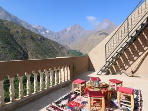 uma varanda com mesa, cadeiras e montanhas em RiadAtlasChateau em Imlil