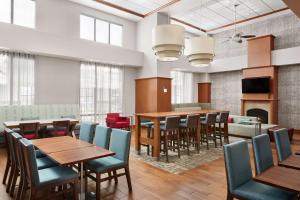 a dining room with tables and chairs and a fireplace at Hampton Inn & Suites West Haven in West Haven