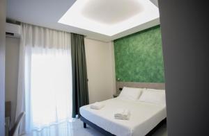 - une chambre avec un lit blanc et un mur vert dans l'établissement Mars B&B, à Milazzo