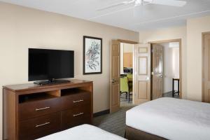 Homewood Suites by Hilton Baltimore-Washington Intl Apt في لينثيكوم هايتس: غرفة نوم بسرير وتلفزيون على دولاب