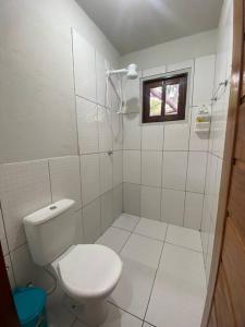 a white bathroom with a toilet and a window at Bangalôs do Tapajós in Alter do Chao