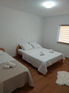 ein weißes Schlafzimmer mit 2 Betten und einem Fenster in der Unterkunft Apartmani Franciska in Jajce