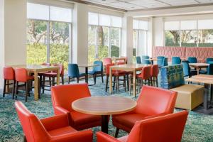 una sala de espera con mesas, sillas y ventanas en Hilton Garden Inn Orlando at SeaWorld, en Orlando