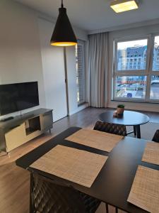 a living room with a table and a tv at Golden Apartments Świętej Barbary in Gdańsk