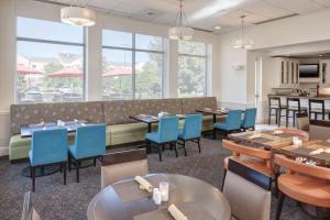 Hilton Garden Inn Savannah Airport في سافانا: غرفة طعام مع طاولات وكراسي ونوافذ