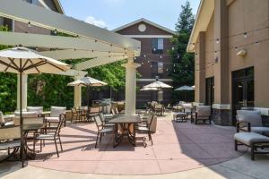 um pátio exterior com mesas, cadeiras e guarda-sóis em Homewood Suites by Hilton Fresno em Fresno