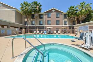 a swimming pool in front of a hotel with palm trees at Homewood Suites by Hilton Fresno in Fresno
