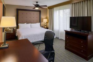 a hotel room with a bed and a desk and a television at Homewood Suites by Hilton Fresno in Fresno