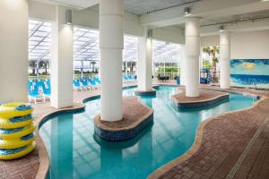 uma piscina com colunas brancas e água azul em Homewood Suites by Hilton Myrtle Beach Oceanfront em Myrtle Beach