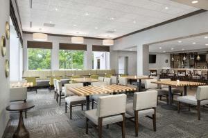 - une salle à manger avec des tables, des chaises et des fenêtres dans l'établissement Hilton Garden Inn Greenville, à Greenville
