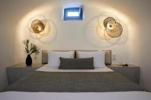 a bedroom with a bed with two mirrors on the wall at Arxegono Cave Houses Santorini in Pyrgos