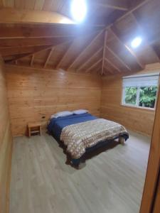 1 dormitorio con 1 cama en una cabaña de madera en Cabaña Los Alerces en Licán Ray