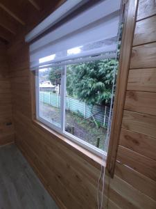 a window in a wooden cabin with a view of a yard at Cabaña Los Alerces in Licán Ray