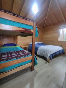 a bedroom with two bunk beds in a log cabin at Cabaña Los Alerces in Licán Ray