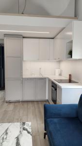 a kitchen with white cabinets and a blue couch at Morze Wyspa in Gdańsk