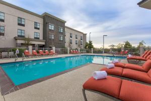 a swimming pool with red lounge chairs next to a building at Hampton Inn & Suites San Diego-Poway in Poway