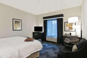 um quarto de hotel com uma cama e uma cadeira e uma janela em Hampton Inn & Suites Bellevue Downtown/Seattle em Bellevue