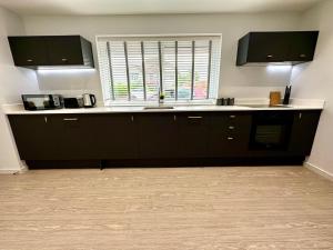 Una cocina con gabinetes negros y un fregadero y una ventana. en Stunning Brand New House - Sleeps 6 - Free Parking - Great Location - Fast WiFi - Smart TV - Close to Poole & Bournemouth & Sandbanks, en Poole