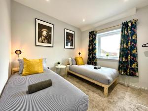 um quarto com 2 camas e uma janela em Stunning Brand New House - Sleeps 6 - Free Parking - Great Location - Fast WiFi - Smart TV - Close to Poole & Bournemouth & Sandbanks em Poole
