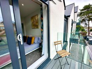 a balcony with a chair and a couch on a porch at Stunning Brand New House - Sleeps 6 - Free Parking - Great Location - Fast WiFi - Smart TV - Close to Poole & Bournemouth & Sandbanks in Poole