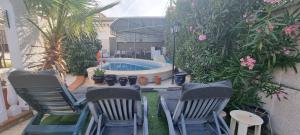 eine Gruppe von Stühlen neben einem Pool in der Unterkunft Villamartin Villa Oasis in Alicante