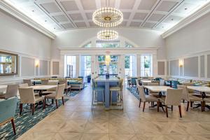 a dining room with tables and chairs and a chandelier at Hampton Inn & Suites South Park at Phillips Place in Charlotte
