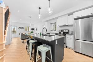 a kitchen with white cabinets and a large island with bar stools at Le Karina - Vieux-Terrebonne in Terrebonne