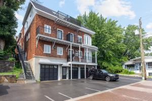 a black car parked in front of a brick building at Le Karina - Vieux-Terrebonne in Terrebonne